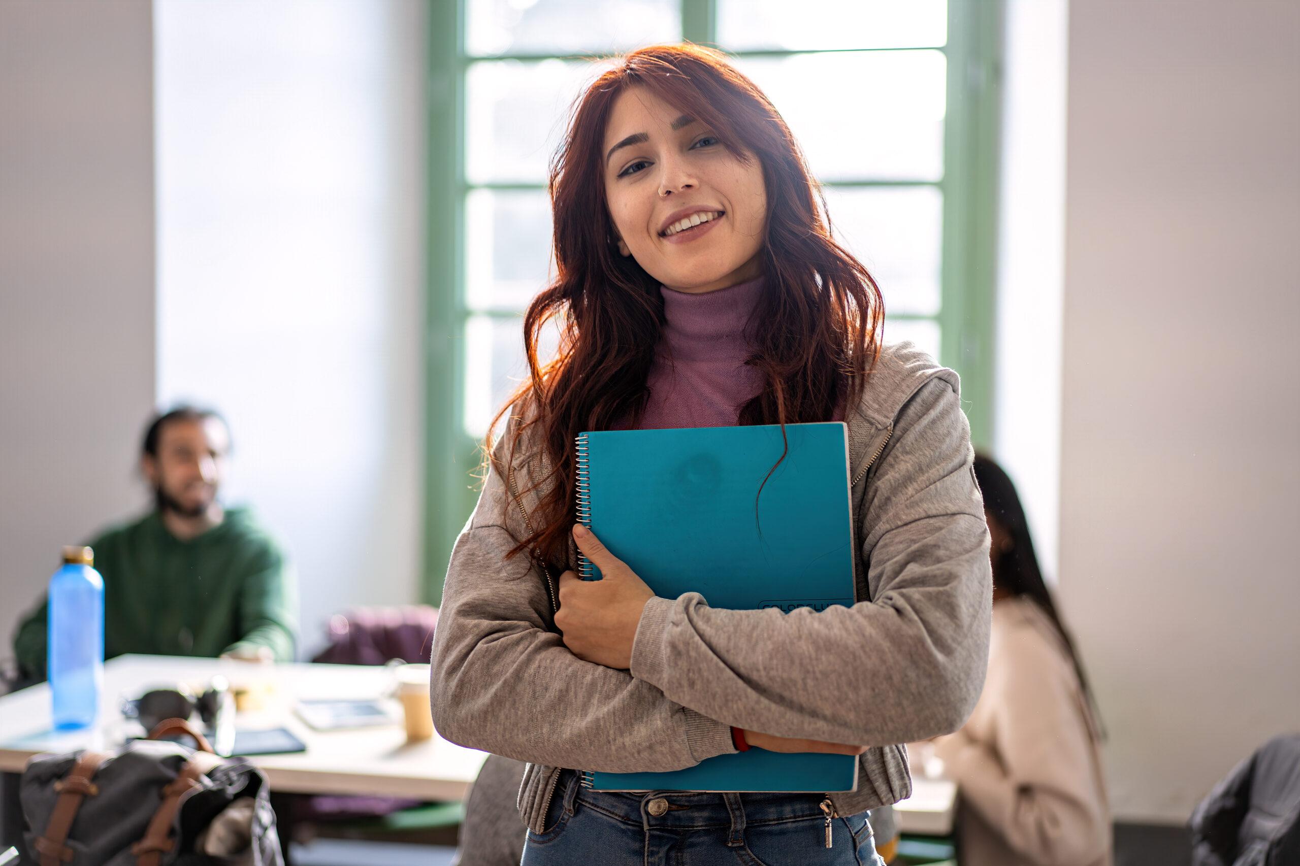 Confident Female Student Holding Notebook in Classroom