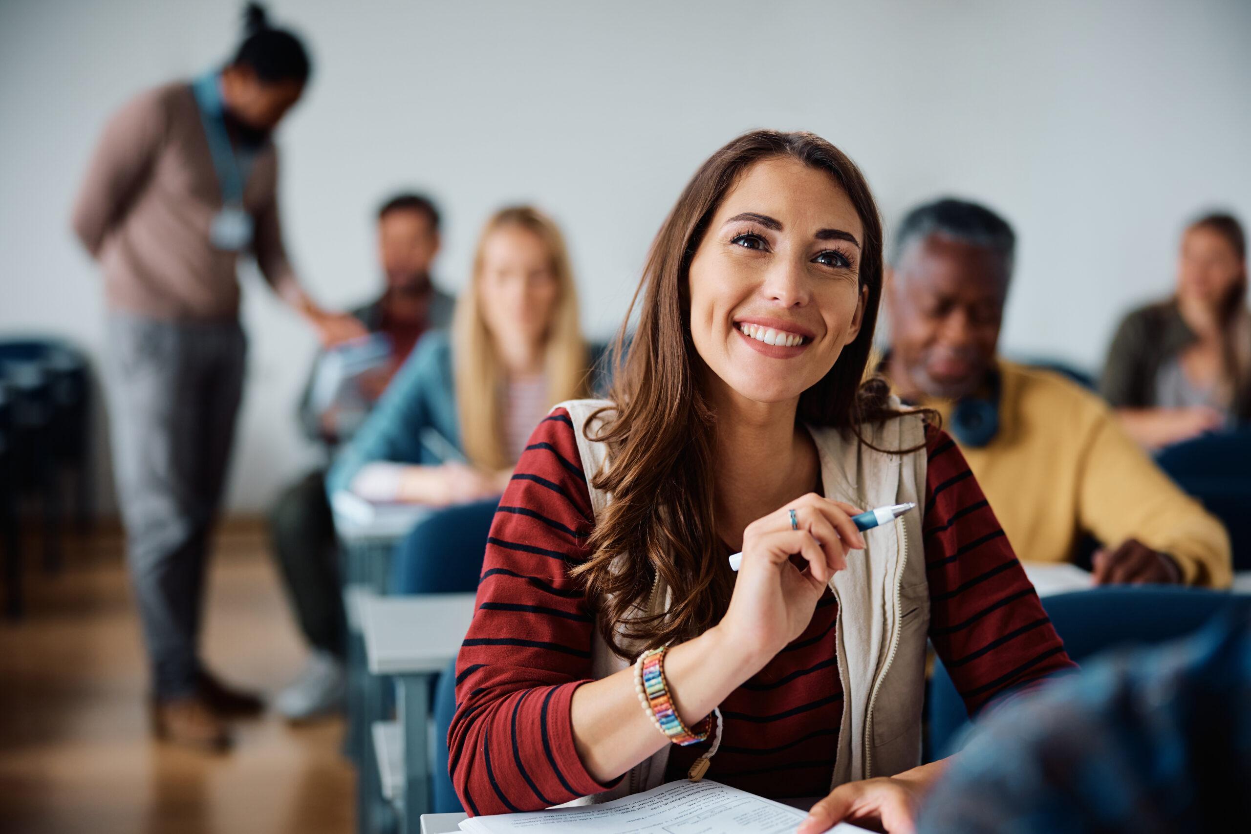 Happy female student attending a class in lecture hall.